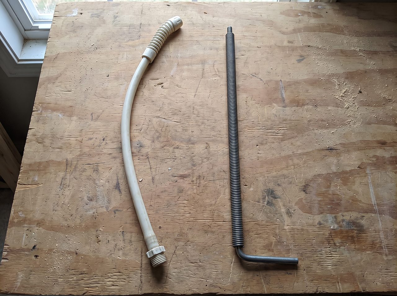 flexible tank wand shown beside a rigid metal plumbing snake for comparison