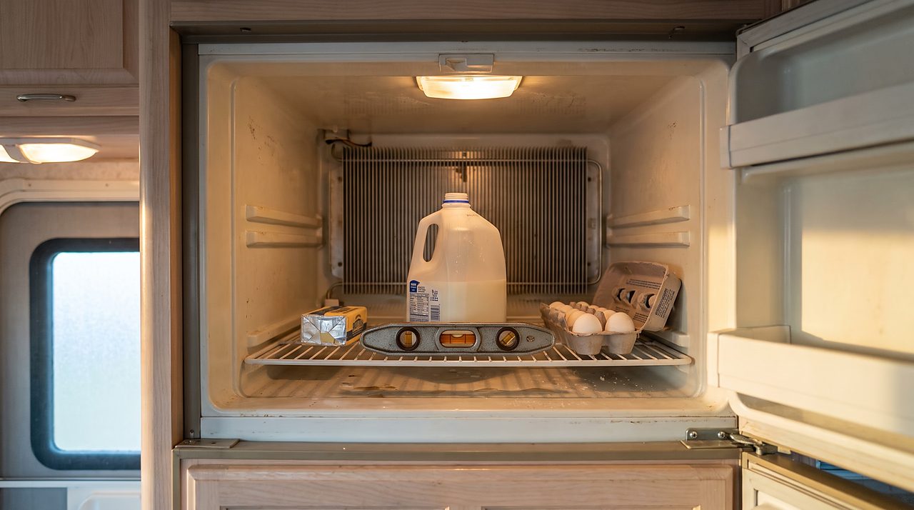 torpedo level on an RV fridge shelf showing the unit sitting slightly out of level