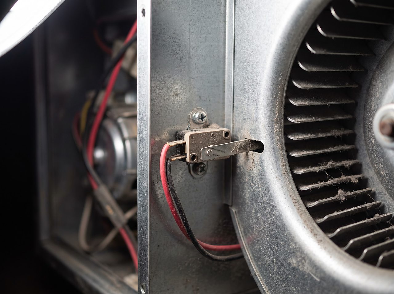 dust-covered sail switch and blower wheel inside an open RV furnace housing
