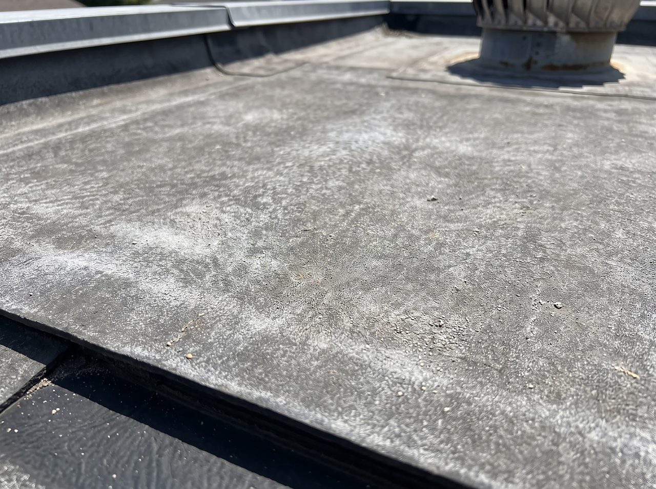 chalky white residue on a sun-faded rubber roof membrane surface