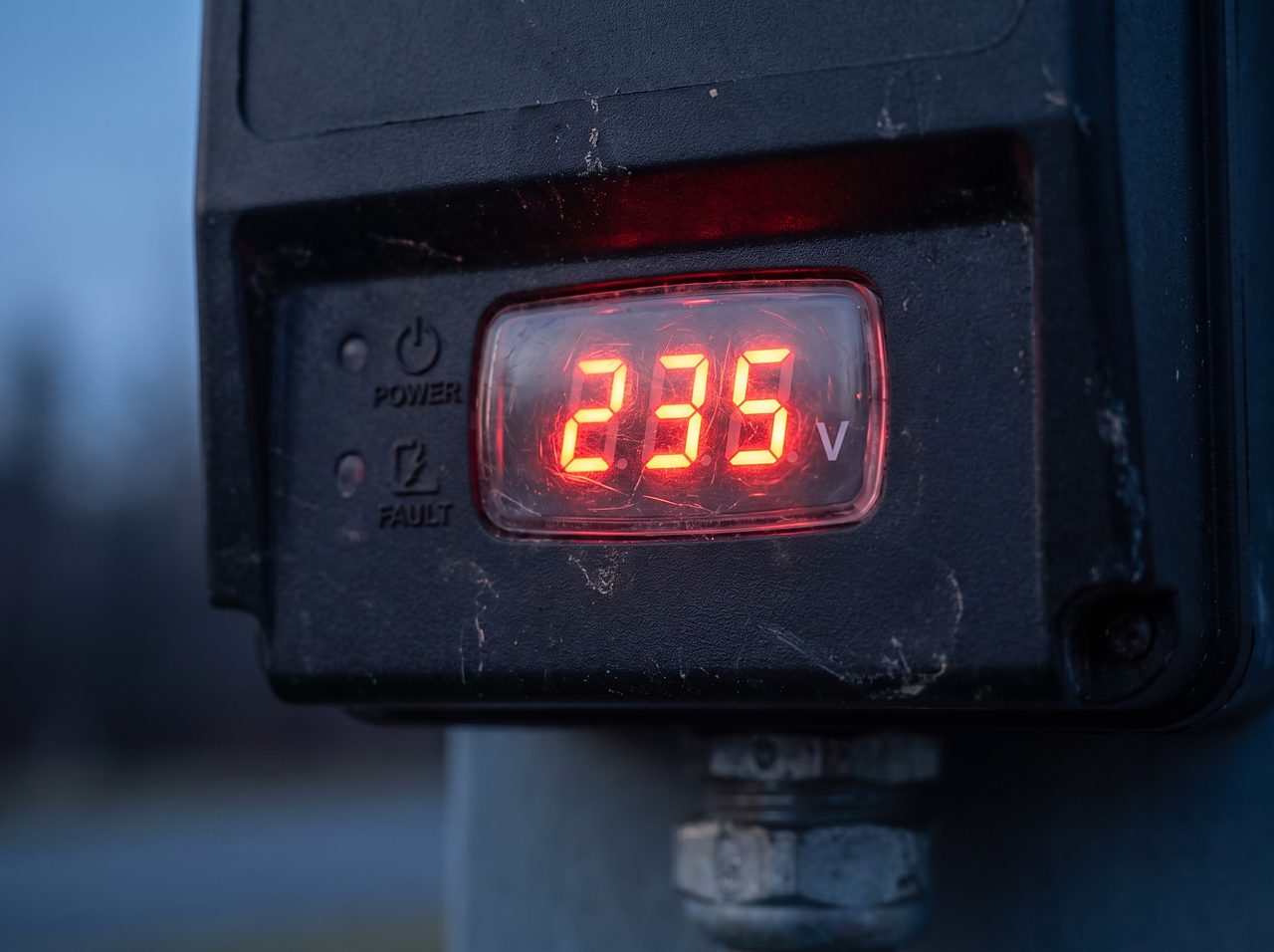 digital voltage display glowing red on an electrical monitoring device at dusk