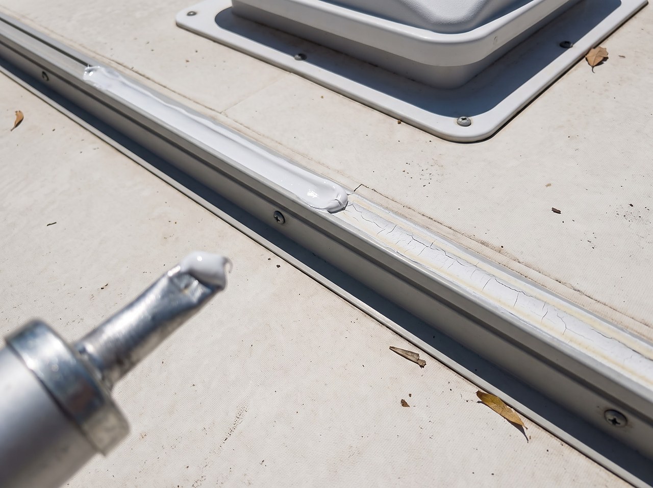 close-up of a roof seam showing fresh and aging lap sealant along a vent base