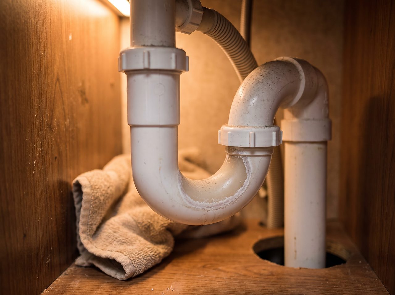 dry white plastic P-trap pipe under an RV bathroom sink cabinet