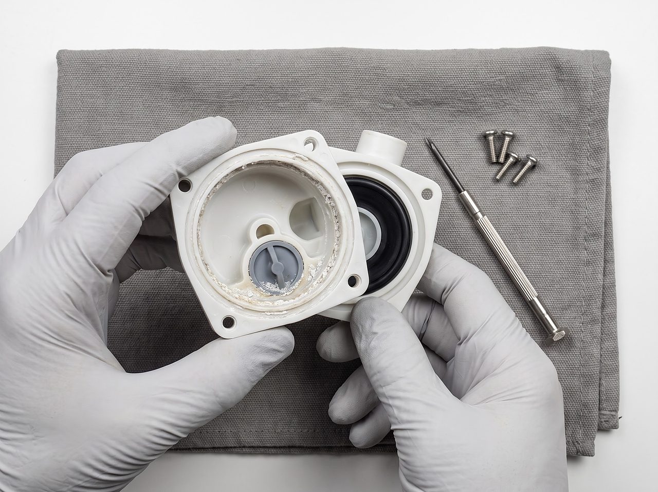 disassembled water pump head showing a worn rubber check valve seat